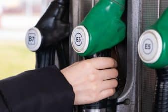 Petrol pump in a petrol station. Close up woman hand take oil dispenser with gasoline and diesel