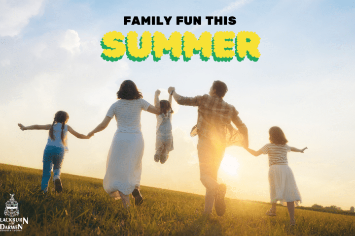 A family of five runs hand in hand across a grassy hill at sunset, with summer fun text and the Blackburn with Darwen Borough Council logo.